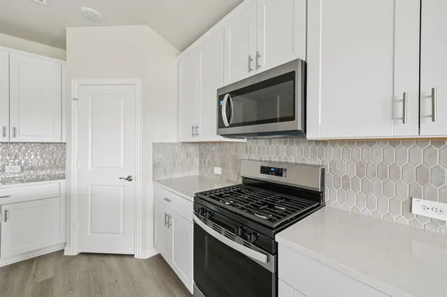 a kitchen with white cabinets and stainless steel appliances
