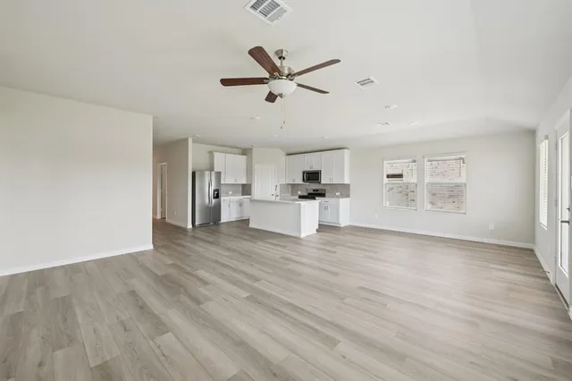 a view of a kitchen with wooden floor a ceiling fan and windows