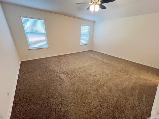 an empty room with windows and chandelier fan
