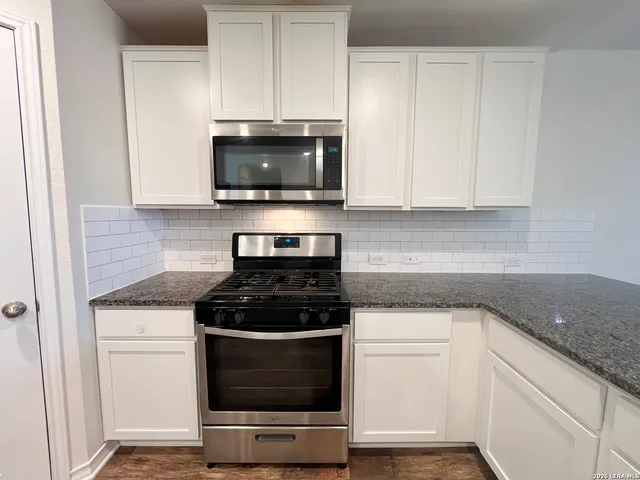 a kitchen with granite countertop cabinets stainless steel appliances and a sink
