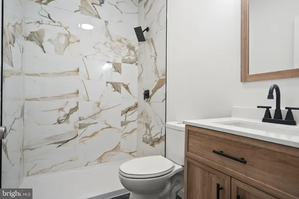 a bathroom with a granite countertop toilet sink and mirror