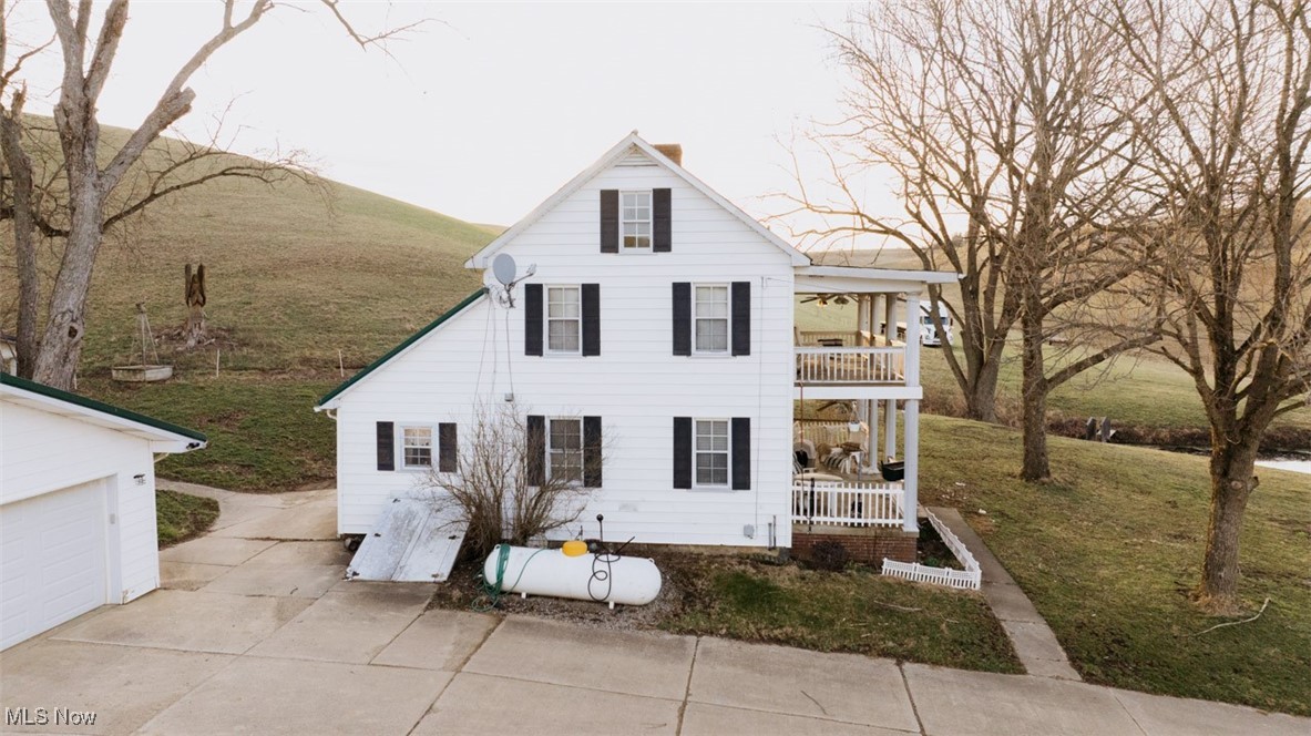 8091 Fargo Road Southwest Dellroy, OH 44620 - Photo 24 of 29 View of side of property featuring concrete driveway, a front yard, a porch, and a balcony