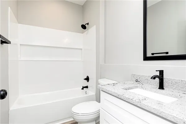 a bathroom with a granite countertop sink a toilet and bathtub