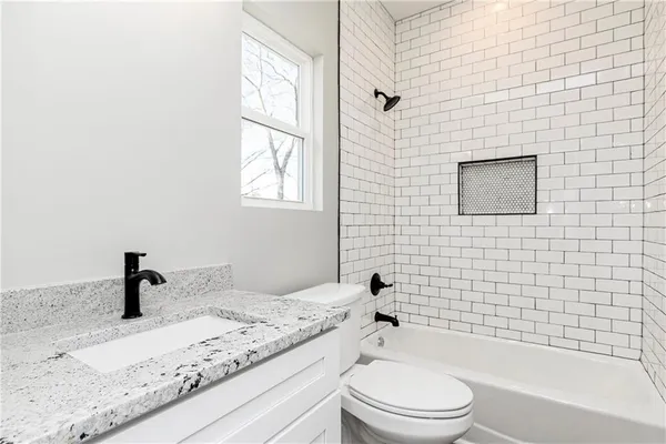a bathroom with a granite countertop toilet a sink and bathtub
