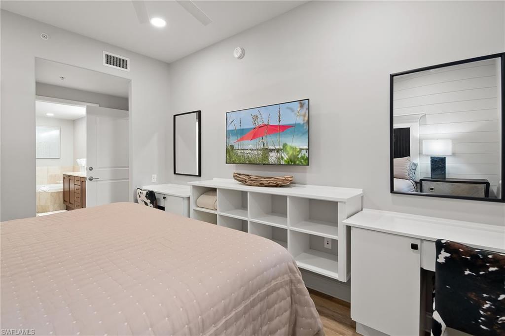 1015 Sandpiper Street, Unit D102 Naples, FL 34102 - Photo 14 of 34 a bedroom with a large bed and a flat tv screen on dresser