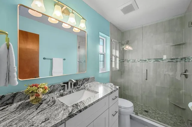 a bathroom with a granite countertop sink toilet and shower
