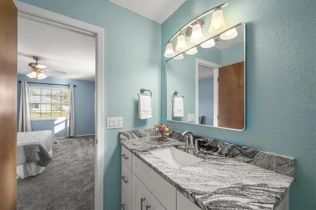 a bathroom with a granite countertop sink and a mirror