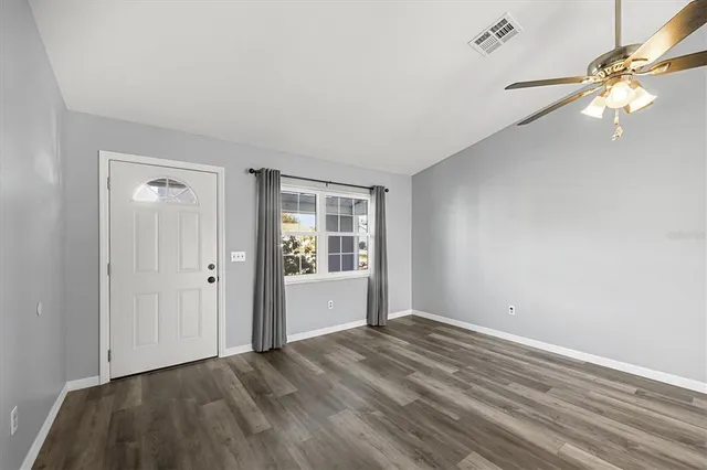 a view of an empty room with window and wooden floor