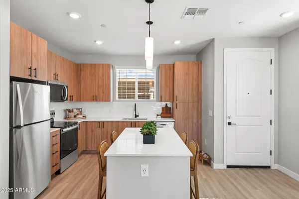 a kitchen with stainless steel appliances granite countertop a refrigerator a sink dishwasher a stove and a refrigerator with wooden floor