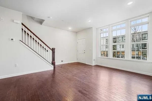 a view of an empty room with wooden floor and stairs
