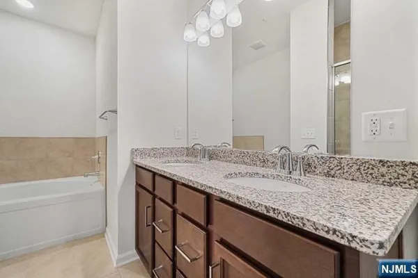 a bathroom with a granite countertop sink and a bathtub
