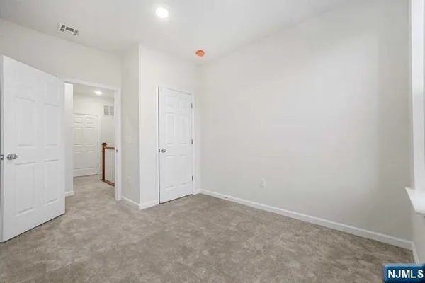 an empty room with white cabinet and mirror