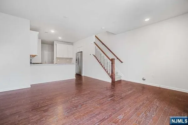 a view of an empty room with wooden floor and stairs