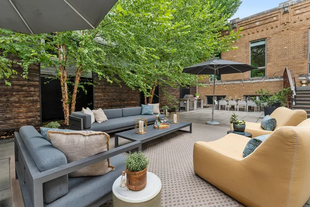 a patio with tables and chairs under an umbrella
