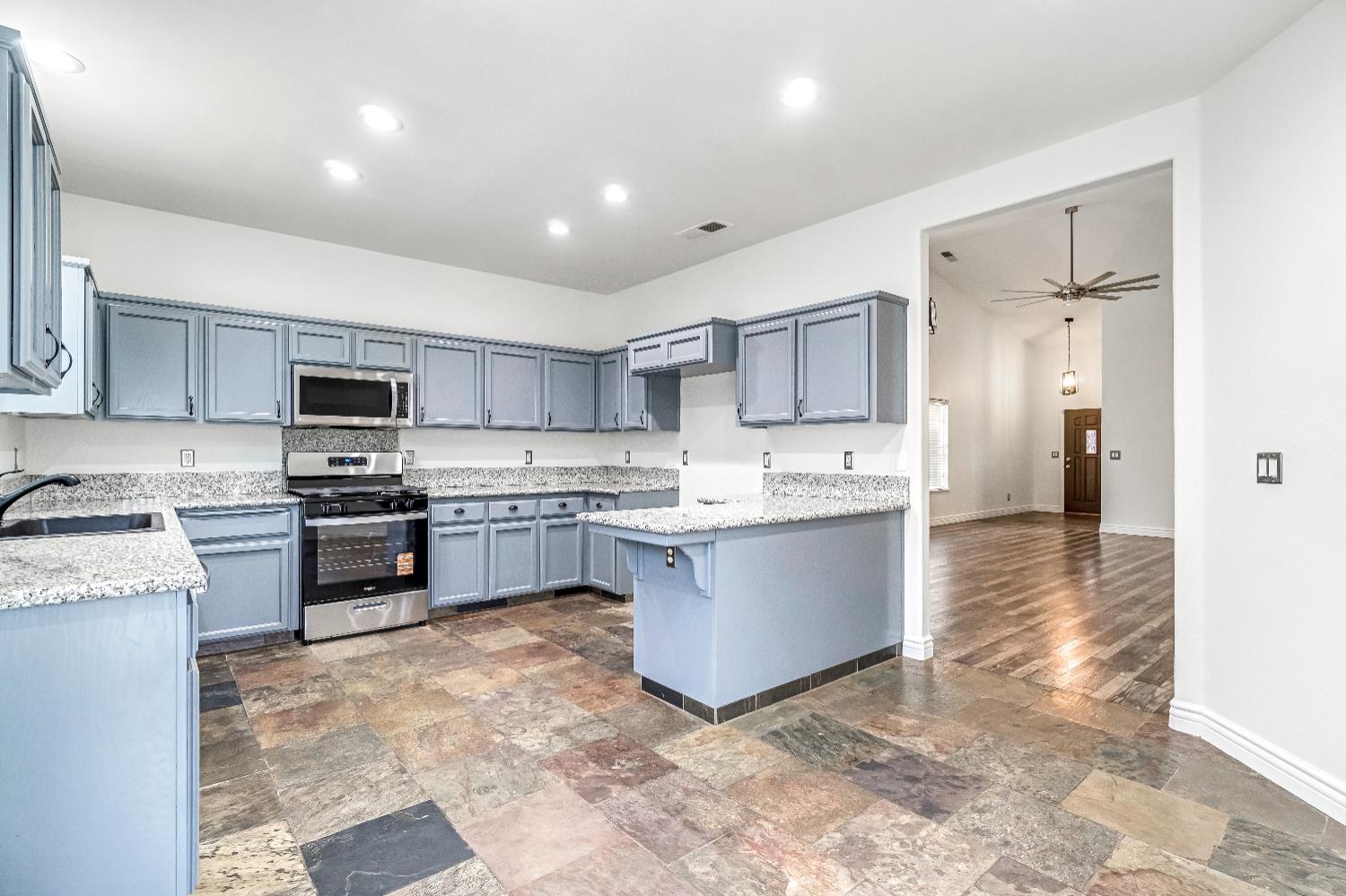 1571 Lemon Avenue Madera, CA 93637 - Photo 11 of 38 a kitchen with kitchen island granite countertop a sink cabinets and stainless steel appliances