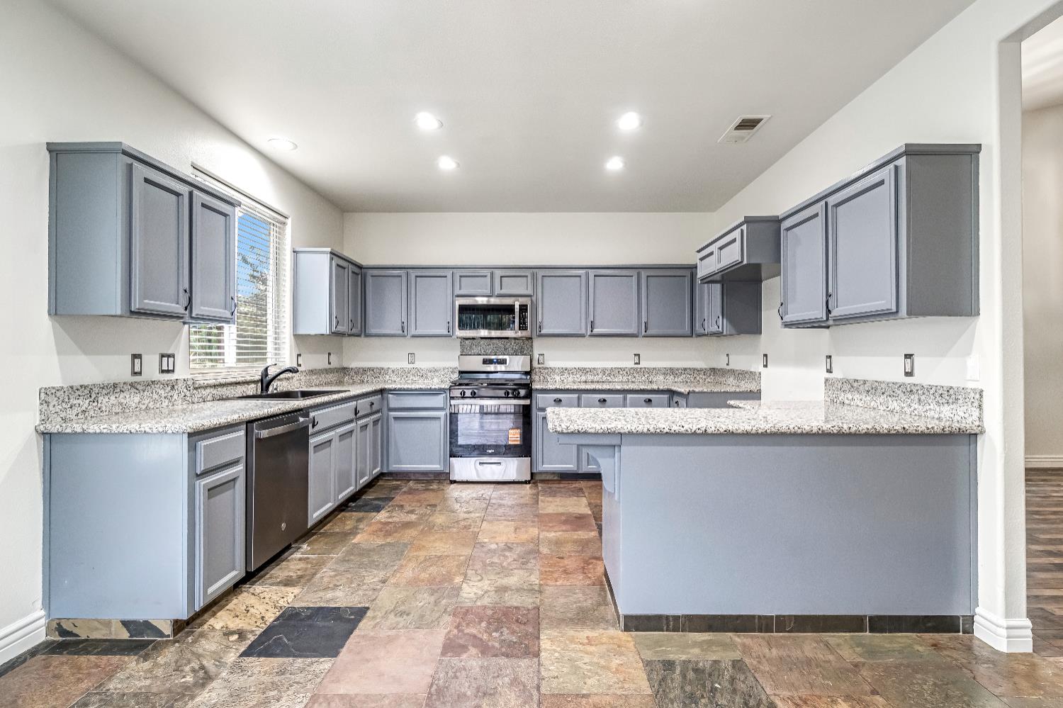 1571 Lemon Avenue Madera, CA 93637 - Photo 12 of 38 a kitchen with stainless steel appliances granite countertop a stove top oven a sink a counter top space and cabinets