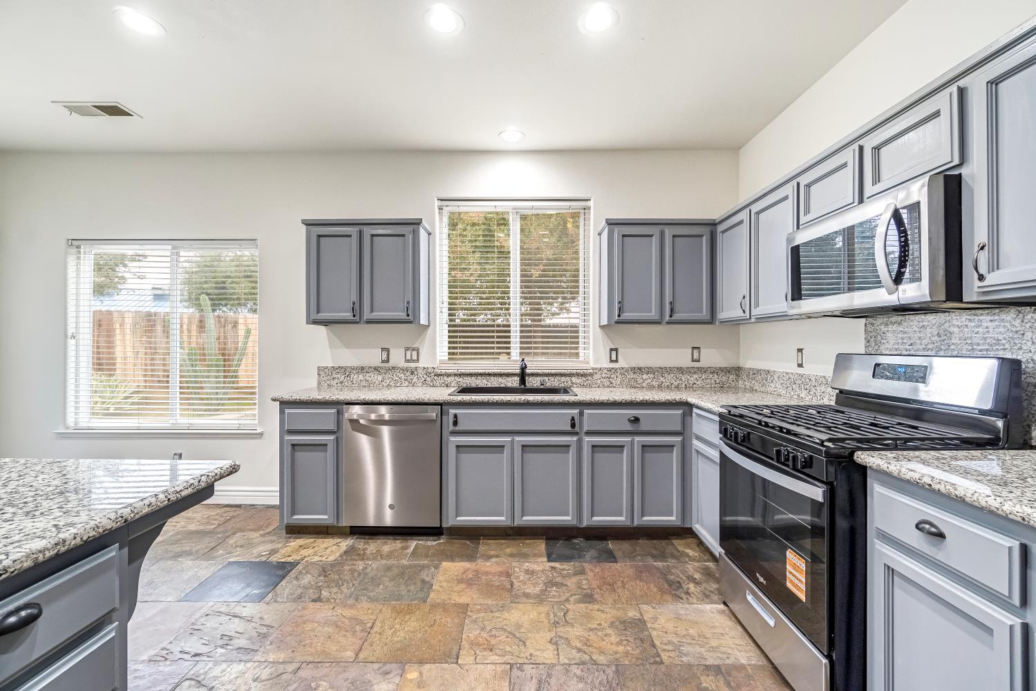 1571 Lemon Avenue Madera, CA 93637 - Photo 14 of 38 a kitchen with stainless steel appliances granite countertop a stove sink and cabinets