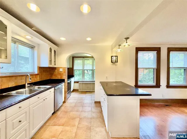 a large kitchen with granite countertop a large counter top stainless steel appliances a sink and a window