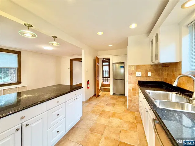 a large kitchen with granite countertop a sink and cabinets