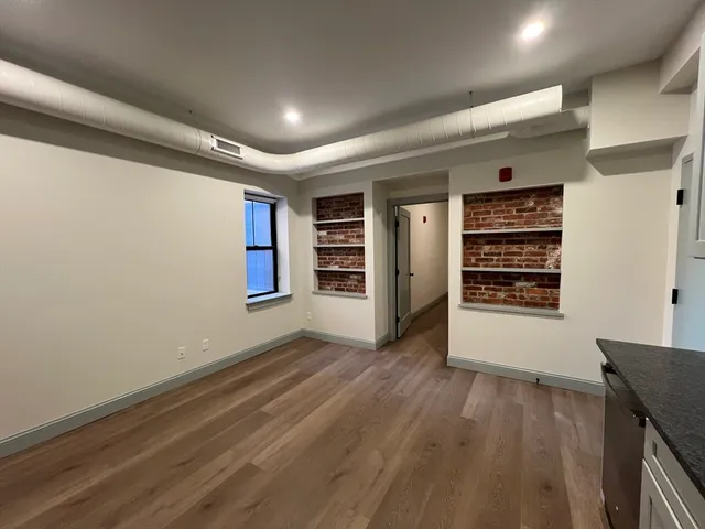 an empty room with wooden floor closet and windows