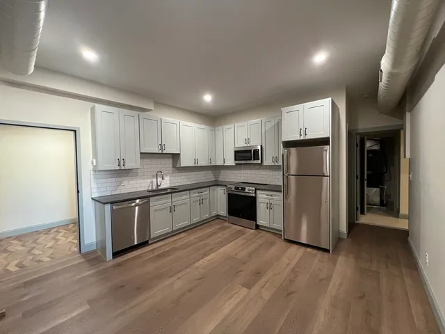 a kitchen with a refrigerator a sink and dishwasher with wooden floor