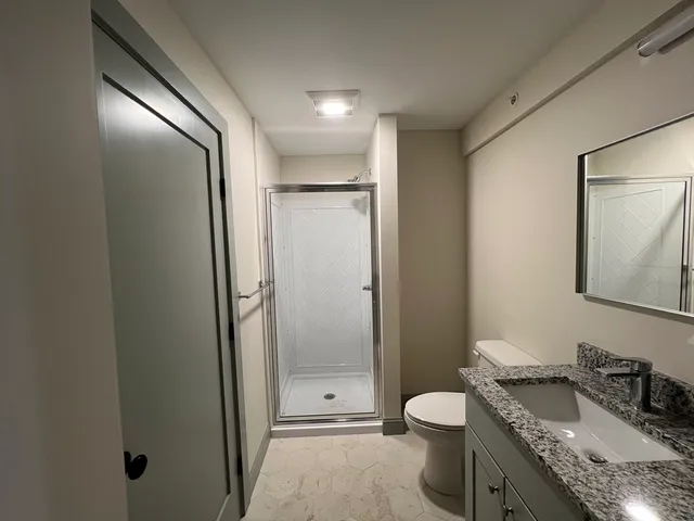 a bathroom with a granite countertop sink toilet and shower
