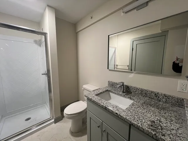 a bathroom with a granite countertop sink toilet and shower