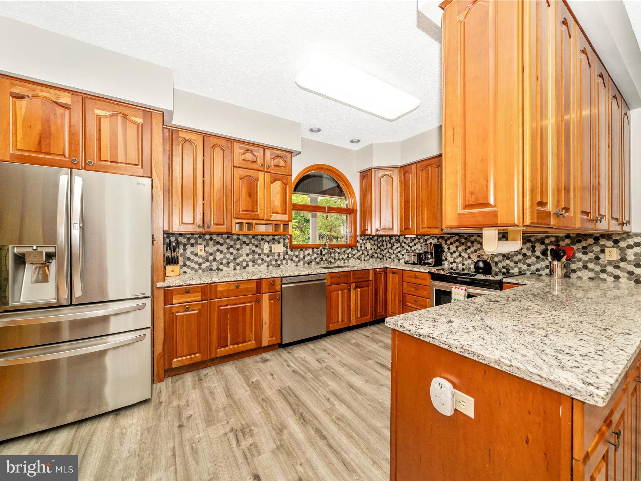 17879 Harbaugh Valley Road Sabillasville, MD 21780 - Photo 10 of 64 a kitchen with stainless steel appliances granite countertop a refrigerator a sink dishwasher a stove with wooden cabinets and floor
