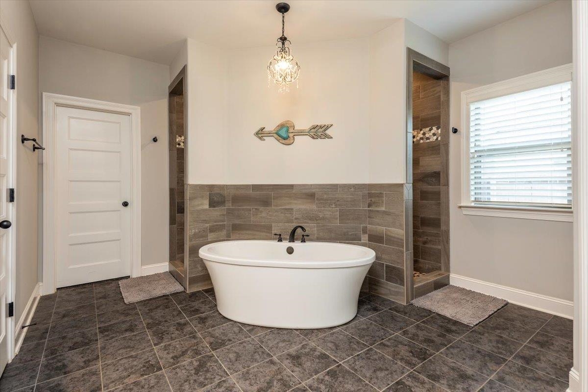 3328 Straw Bridge Road Olive Branch, MS 38654 - Photo 21 of 28 Freestanding soaking tub with dark-toned fixtures, dual showers with tiled surrounds, and large format floor tiling