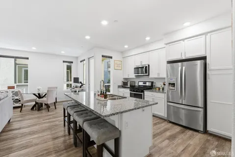 a kitchen with granite countertop a refrigerator a stove a sink a dining table and chairs