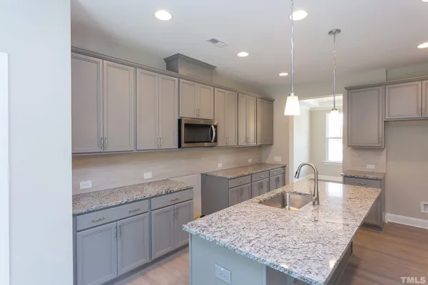 a kitchen with kitchen island granite countertop a sink stainless steel appliances and white cabinets