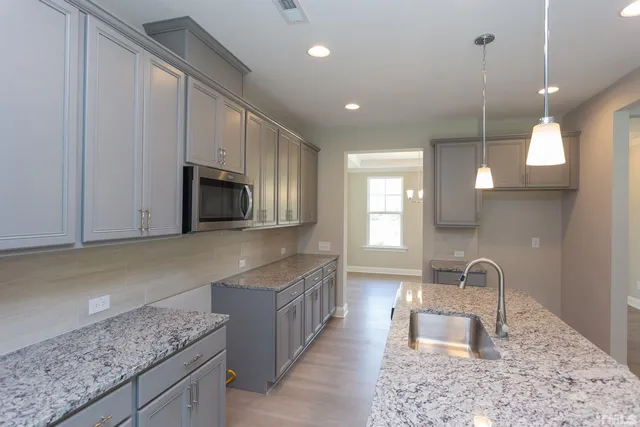 a kitchen with kitchen island granite countertop a sink a stove and a wooden cabinets