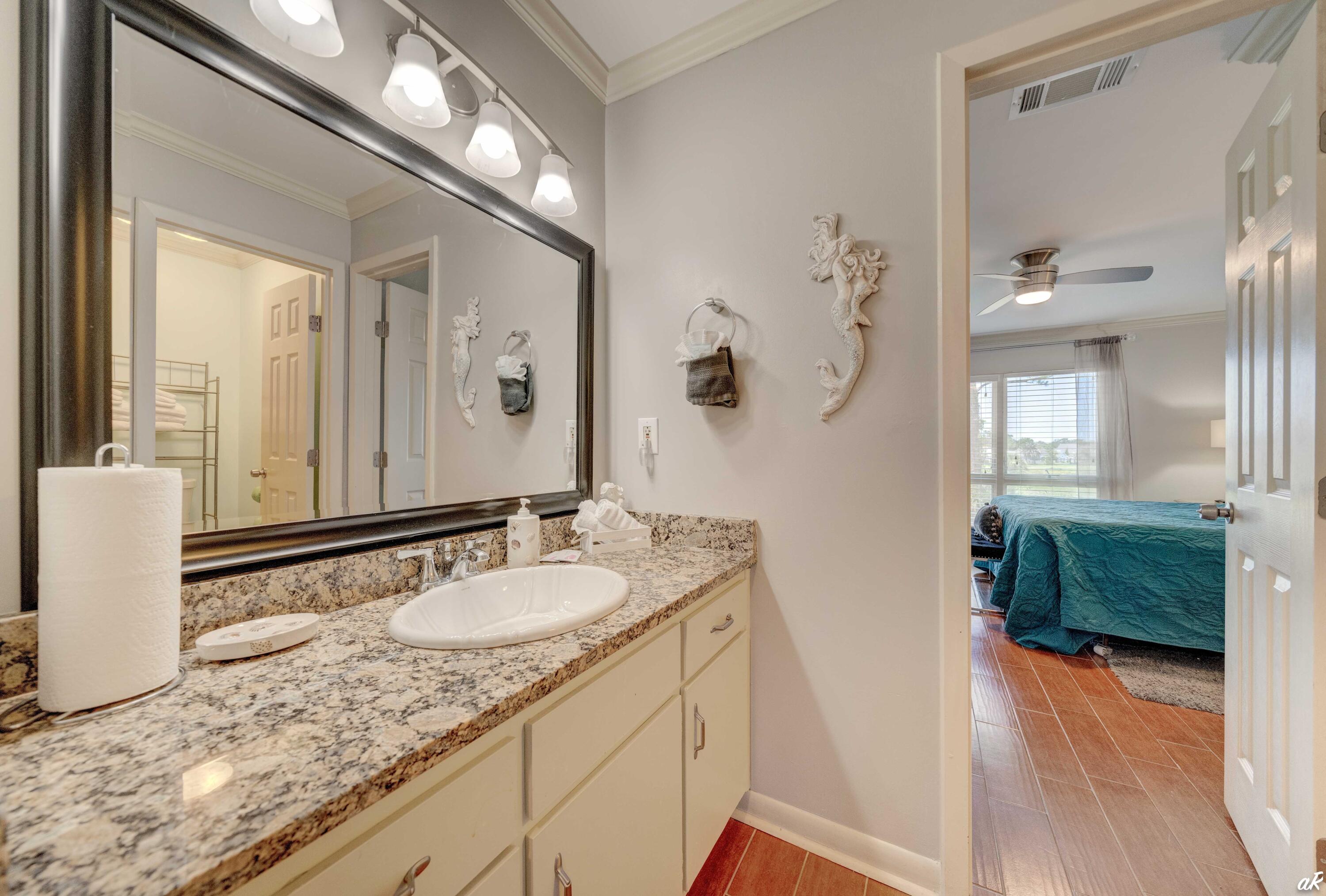 4300 Bay Point Road, Unit 417 Panama City Beach, FL 32408 - Photo 15 of 35 a bathroom with a granite countertop sink a mirror and a shower