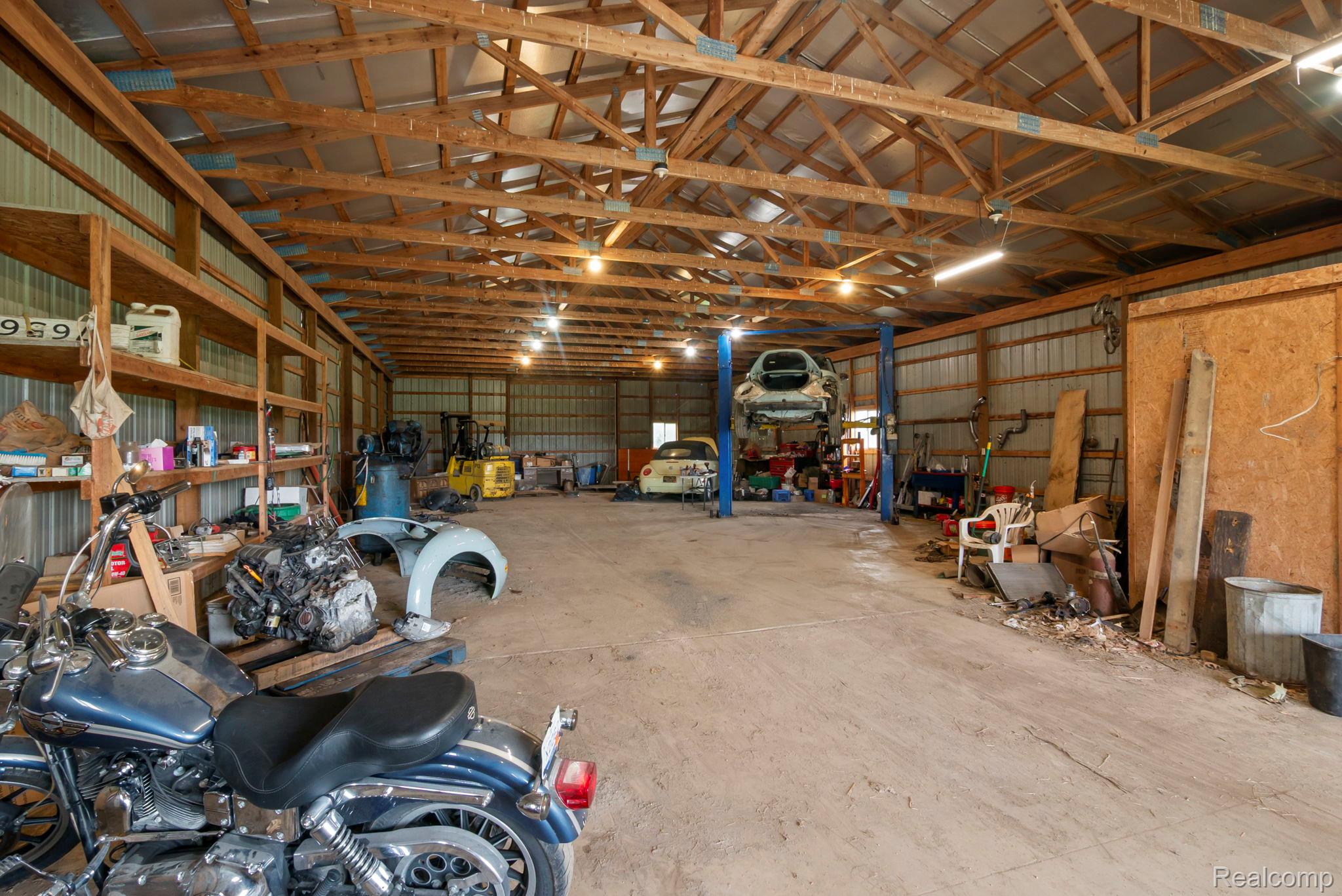 76565 McFadden Road Armada, MI 48005 - Photo 59 of 95 Spacious workshop with exposed wood beam ceiling, corrugated metal walls, concrete flooring, and ample lighting