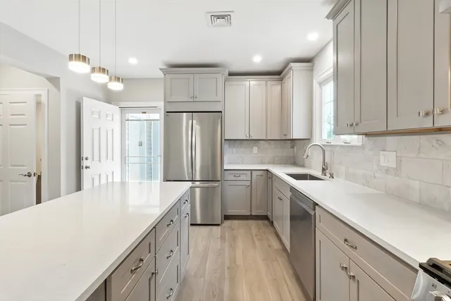 a kitchen with a sink a refrigerator and white cabinets