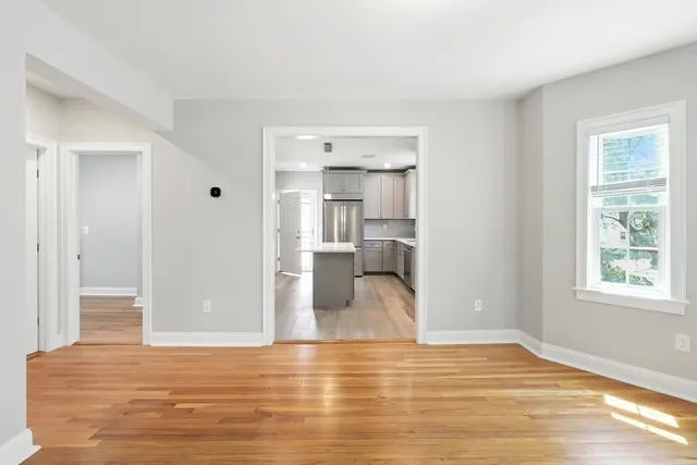 a view of empty room with wooden floor and windows