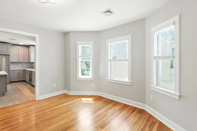 an empty room with wooden floor closet and windows