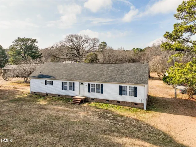 a view of a house with a big yard and large tree