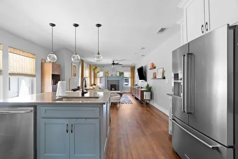 a kitchen with stainless steel appliances kitchen island granite countertop a refrigerator a sink dishwasher a oven and a dining table with wooden floor