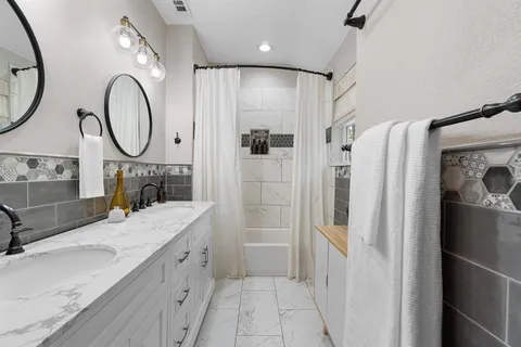 a spacious bathroom with a granite countertop sink a mirror a vanity and a shower
