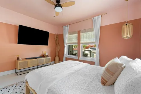 a bedroom with a bed a flat screen tv and a window