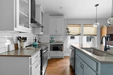 a kitchen with granite countertop a sink a counter space appliances and cabinets