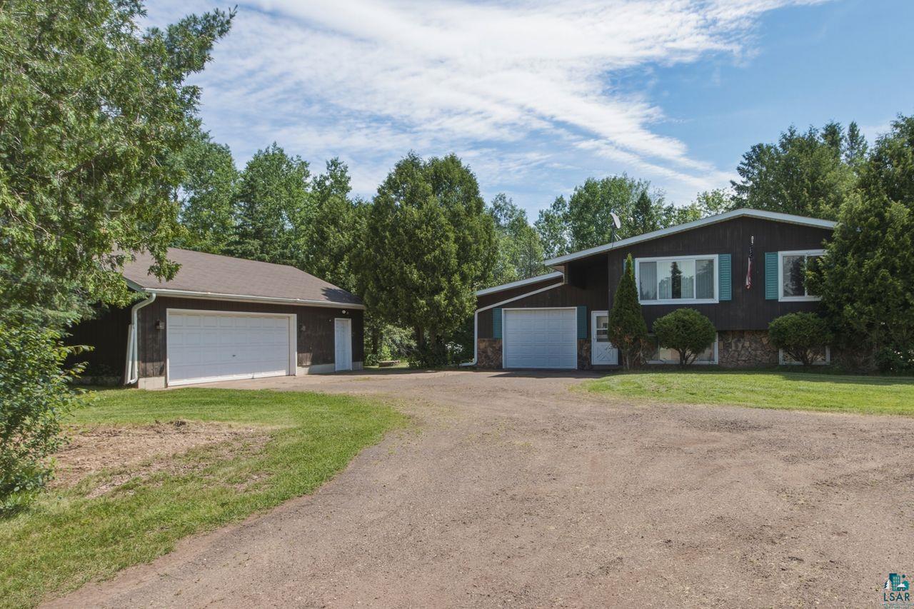 61018 Dahlstrom Road Ashland, WI 54806 - Photo 27 of 28 Two-story dark siding residence featuring a stone foundation, multiple white-framed windows with light blue shutters, and an attached two-car garage