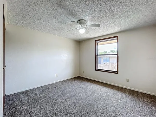 an empty room with chandelier fan and windows