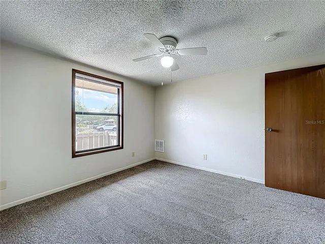 an empty room with ceiling fan and window
