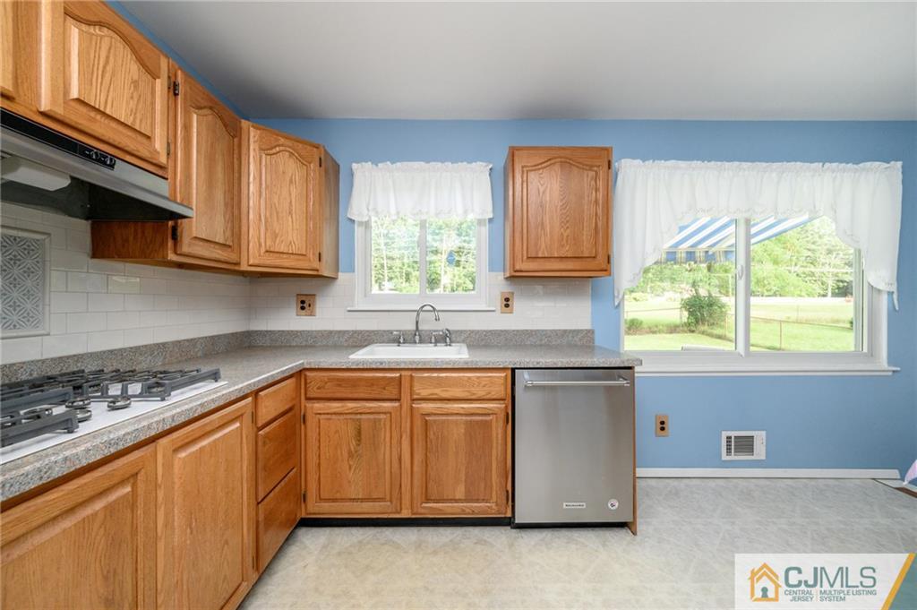 25 Drexel Drive Jackson, NJ 08527 - Photo 9 of 34 a kitchen with stainless steel appliances granite countertop a sink a stove a microwave cabinets and a window