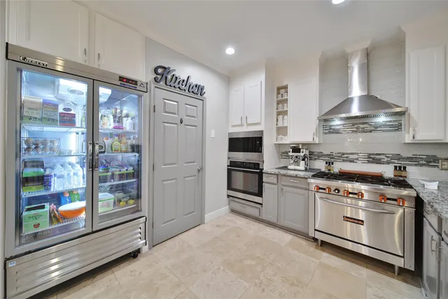 a kitchen with stainless steel appliances a refrigerator stove and white cabinets