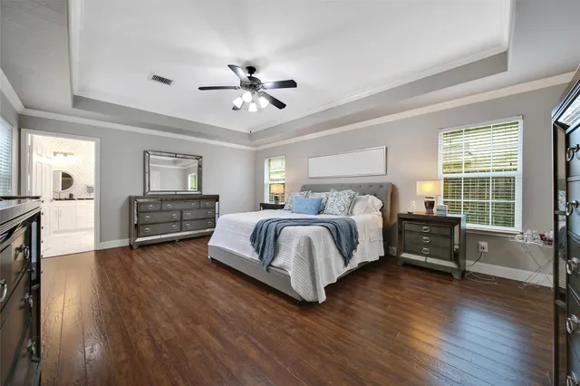 a spacious bedroom with a bed a dresser and wooden floor