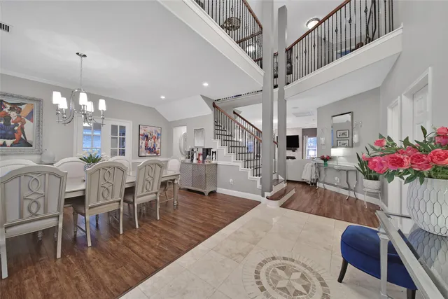 a living room with furniture dining table wooden floor and a chandelier