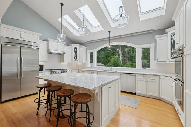 a kitchen with stainless steel appliances kitchen island granite countertop a table chairs sink and cabinets